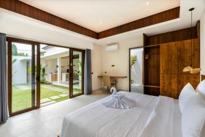 J4 Villas Sanur في سانور: غرفة نوم بسرير أبيض كبير وأبواب زجاجية منزلقة