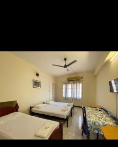 a bedroom with two beds and a ceiling fan at Aambal Residency in Cochin