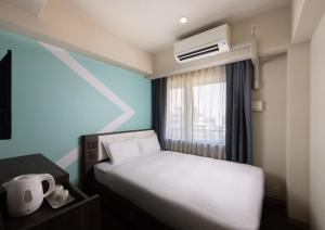 a small bedroom with a bed and a window at ibis Budget Osaka Umeda in Osaka