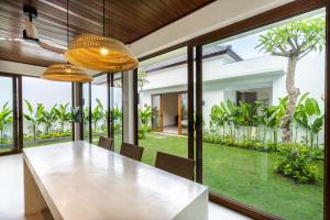an open dining room with a table and chairs and large windows at J4 Villas Sanur in Sanur