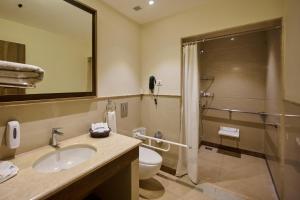 a bathroom with a sink and a toilet and a shower at Flora Airport Hotel and Convention Centre Kochi in Nedumbassery