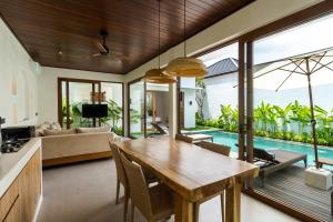 an open kitchen and living room with a wooden dining table at J4 Villas Sanur in Sanur