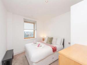 a white bedroom with a bed and a window at Pass the Keys Waterfront Serenity Leeds Dock Christmas Views in Leeds
