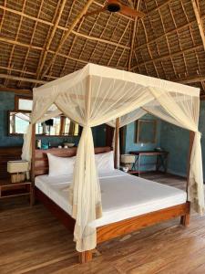 a bed with a canopy in a room at TIKI Beach Club & Resort in Bwejuu