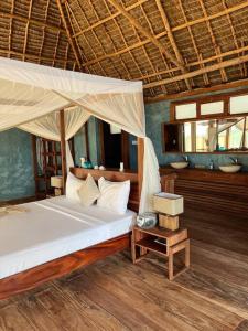ein Schlafzimmer mit einem Himmelbett in der Unterkunft TIKI Beach Club & Resort in Bwejuu