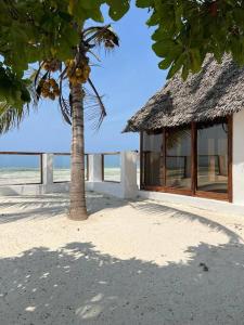 ein Gebäude mit einer Palme neben einem Strand in der Unterkunft TIKI Beach Club & Resort in Bwejuu