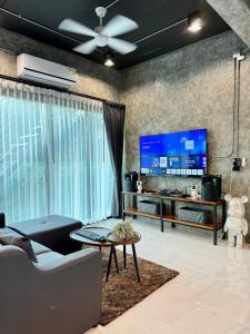 a living room with a couch and a large tv at NADON VILLA in Ban Choko