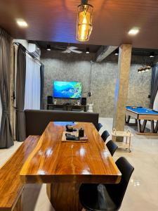 a dining room with a wooden table and a tv at NADON VILLA in Ban Choko