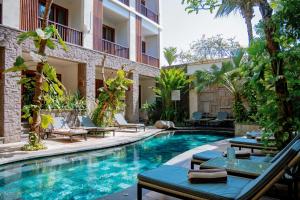 a pool at a hotel with lounge chairs and a resort at Akana Boutique Hotel in Sanur