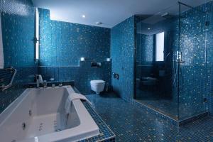 a blue tiled bathroom with a tub and a shower at Kenzi Solazur in Tangier