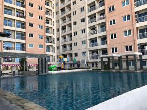 2BR Apartment at Puncak Bukit Golf Surabaya near Lenmarc Mall By Travelio في سورابايا: مسبح امام مبنى سكني كبير