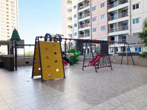 2BR Apartment at Puncak Bukit Golf Surabaya near Lenmarc Mall By Travelio في سورابايا: ملعب مع زلاجة وأرجوحة