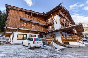 a house with a car parked in front of it at Majon Garneté Buffaure 5 in Pozza di Fassa