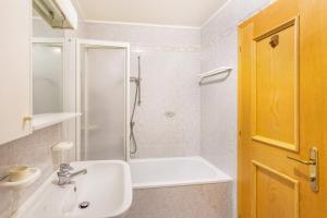 een witte badkamer met een douche en een wastafel bij Majon Garneté Buffaure 5 in Pozza di Fassa