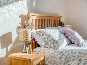 3 Bed in Barnstaple 77506 في Bishops Tawton: سرير مع وسائد و إناء من الزهور على طاولة