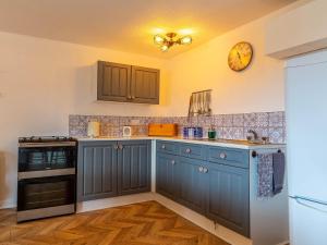 a kitchen with blue cabinets and a clock on the wall at 3 Bed in South Molton 78304 in Kings Nympton
