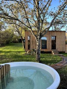 eine Badewanne im Hof mit einem Baum und einem Haus in der Unterkunft Les cabanes de Julie in Lissac et Mouret
