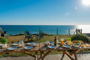 a wooden table with plates of food and a view of the ocean at Sound of the Sea, beach front Bungalow with hot tub, in Tywyn in Tywyn