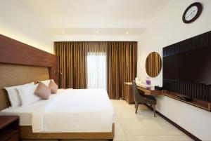 a hotel room with a large bed and a desk at Flora Airport Hotel and Convention Centre Kochi in Nedumbassery