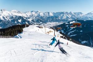 two people skiing down a snow covered ski slope at Studio mit großer Loggia in Saalfelden am Steinernen Meer