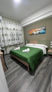 una camera da letto con un letto verde e asciugamani di ALMA B&B Cosenza CENTRO a Cosenza