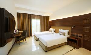 a hotel room with two beds and a desk at Flora Airport Hotel and Convention Centre Kochi in Nedumbassery