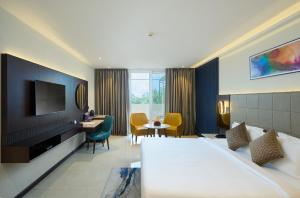 a hotel room with a bed and a television at Flora Airport Hotel and Convention Centre Kochi in Nedumbassery
