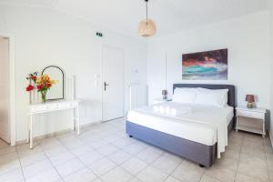 een witte slaapkamer met een bed en een vaas met bloemen bij Filalithis Studios & Apartments in Sami