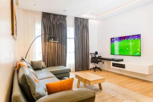 a living room with a couch and a tv at Lakehouse Apartment - Lake Baikal - One Bedroom Apartment in Abuja