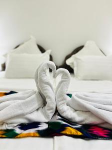 a bed with white towels forming a heart on it at Hotel Lola in Bukhara