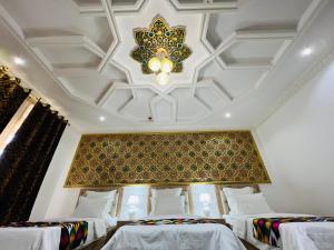 a room with three beds and a ceiling at Hotel Lola in Bukhara