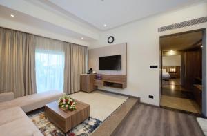 a living room with a couch and a tv at Flora Airport Hotel and Convention Centre Kochi in Nedumbassery