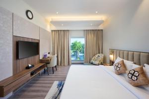 a hotel room with a bed and a television at Flora Airport Hotel and Convention Centre Kochi in Nedumbassery