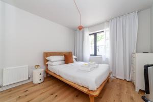 a white bedroom with a large bed with wooden floors at Beautifully renovated 1BR Flat in Walthamstow in London