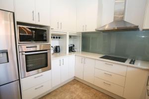 uma cozinha com armários brancos e electrodomésticos de aço inoxidável em 22 Riverside em Bright