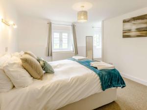 una camera da letto con un grande letto bianco con cuscini di 3 Bed in Bude 83223 a Marhamchurch