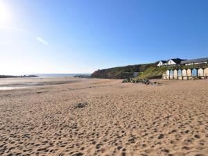 una spiaggia sabbiosa con fila di capanne sulla spiaggia di 3 Bed in Bude 83223 a Marhamchurch