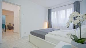 a white bedroom with a bed and a mirror at Mountain Hideaway Apartment in Braşov