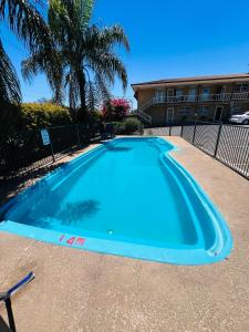 a large blue swimming pool in front of a building at OVERLANDER MOTOR LODGE in Gunnedah