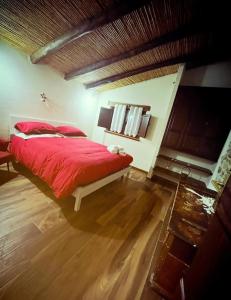 a bedroom with a red bed and a wooden floor at Ovostolai Cottage in Fonni