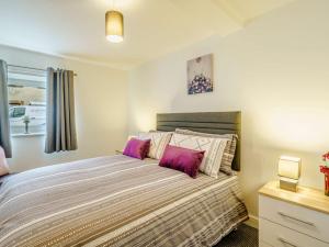 a bedroom with a large bed with purple pillows at 2 Bed in Cockermouth 85514 in Cockermouth