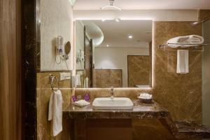 a bathroom with a sink and a large mirror at Flora Airport Hotel and Convention Centre Kochi in Nedumbassery