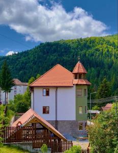 um grande edifício branco com um telhado vermelho em Pensiunea Violin Panzió em Băile Tuşnad