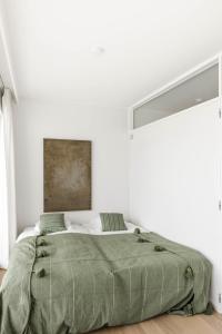 a white bedroom with a green blanket on a bed at LuxuryapartmentSoulforSea in De Panne