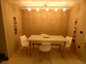 uma mesa de jantar com cadeiras brancas e luzes em Senza Pressa b&b em Portici