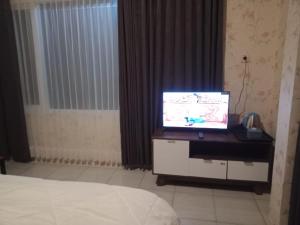 um quarto com uma televisão numa secretária com uma cama em NK Villa Syariah And Cafe Prigen em Pasuruan
