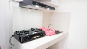 a kitchen with a stove and a sink at Comfy 2BR Apartment at Puncak Kertajaya Surabaya near ITS By Travelio in Surabaya