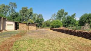 a house with a stone wall and a yard at HOLLYBROOKE Campsites in Skeerpoort +38 photos
