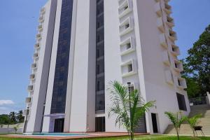 a white building with a palm tree in front of it at Luxurious Penthouse With Luxurious Pool in Takoradi