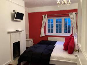 a bedroom with a bed with red walls and a fireplace at Amazing 100 year old church Rectory in Brentwood